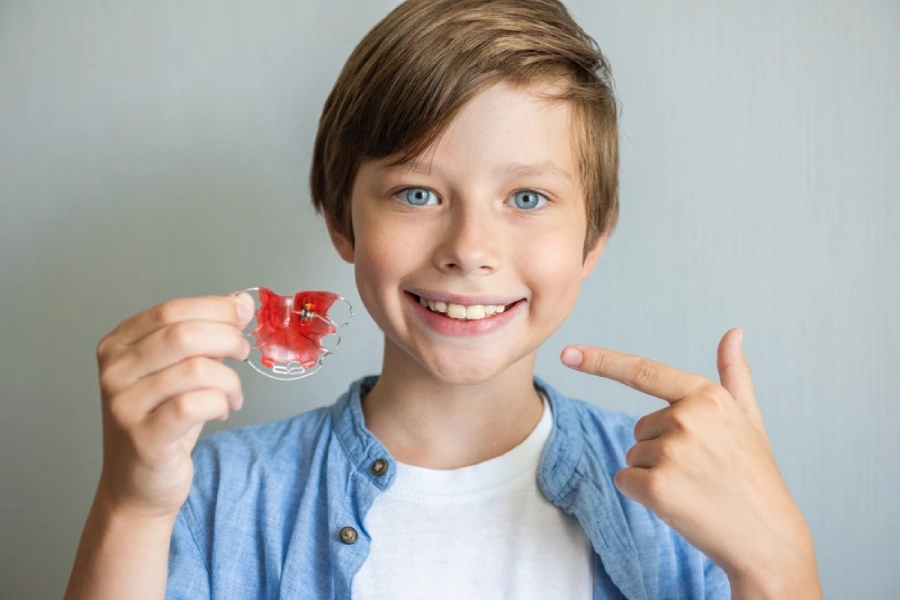 A boy holding his retainer