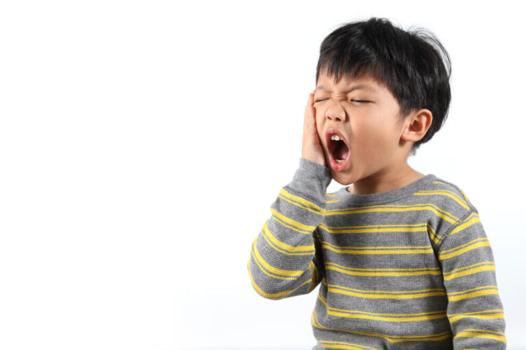 Little boy gesturing in pain from a possible toothache