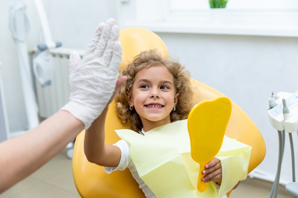 Pedodontist high fives young female patient 