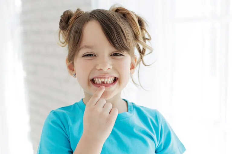 A little girl pointing at her missing tooth